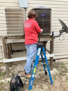 A Roberts Air Conditioning team member servicing an outdoor air conditioning unit