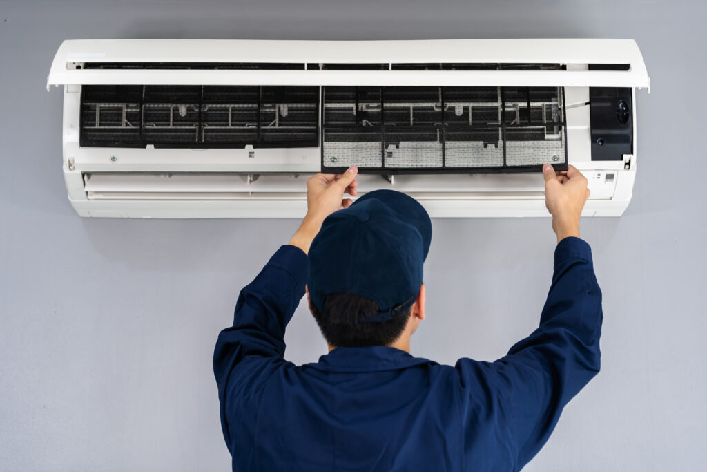 A technician performing maintenance on an indoor ductless air conditioning unit