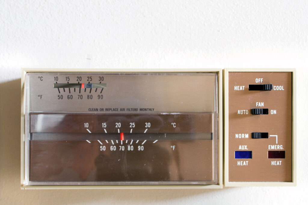 A picture of an older indoor thermostat control unit for heating and air conditioning