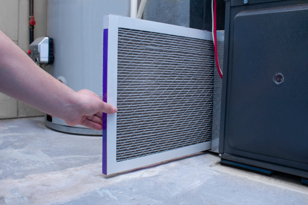 An fresh air filter being inserted into a high efficiency furnace