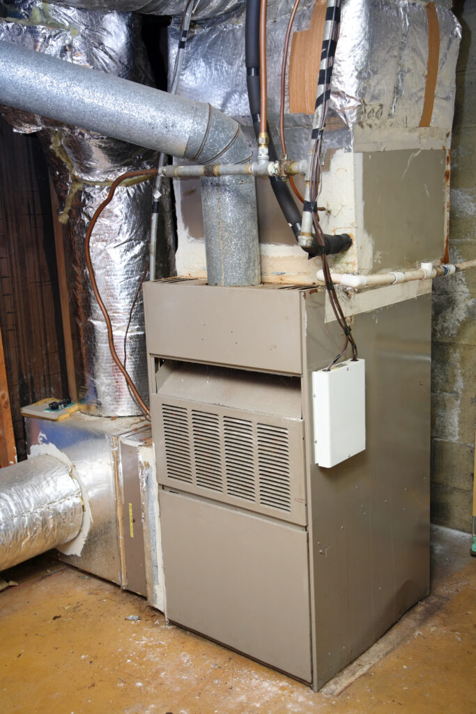 A picture of an old gas furnace in a basement in need of replacement