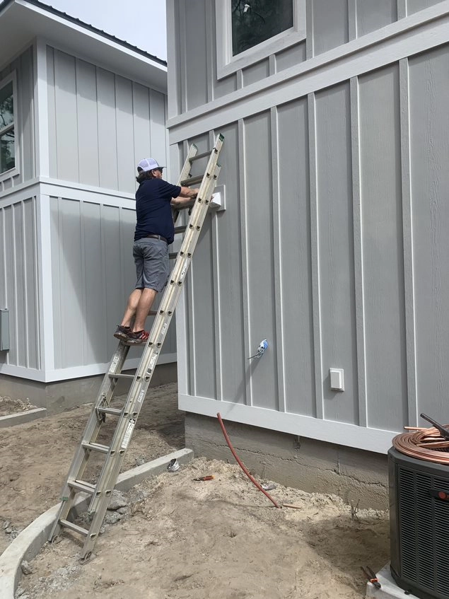 A picture of a technician climbing a ladder to perform maintenance on an outside vent